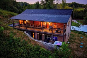 A two-story log cabin with a balcony and a hot tub. - More than Swimming in the Smokies (Seymour)