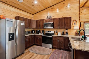 A compact kitchen with wooden cabinets, stainless steel appliances, and a granite countertop.