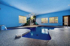 Uma área de piscina com parede azul, um mural de um urso e uma cadeira.