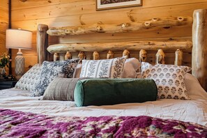 Un lit avec une tête de lit en bois, plusieurs oreillers et une couverture violette.