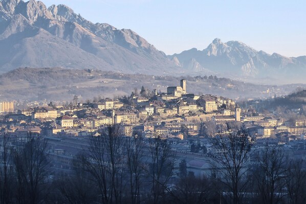 A town with a prominent tower on a hill, surrounded by mountains. - La casa di Valbelluna (Feltre)