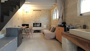 A compact living space with a stone fireplace, a kitchenette, a dining area, and a staircase. - La casa di Valbelluna (Feltre)