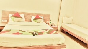 A hotel room with a bed, a sofa, and a nightstand with a bottle and glasses. - Hote SVL (Indore)