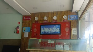 A reception desk with clocks showing different time zones, a notice about CCTV surveillance, and a no smoking sign. - Hote SVL (Indore)