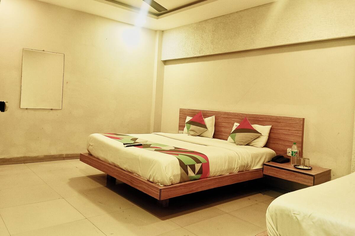 A bedroom with a wooden bed, a nightstand, a ceiling fan, and a wall-mounted light fixture.