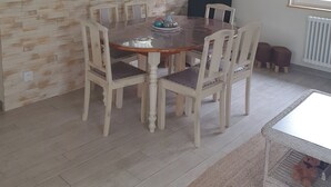 A dining area with a wooden table and chairs, a mirror above the table, and two wall clocks.