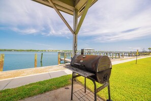 Zona de parrilla techada con vista a un lago y un muelle al fondo.