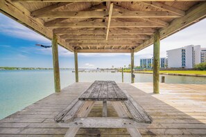 Un muelle de madera con un banco, que da a una vista del frente marítimo.