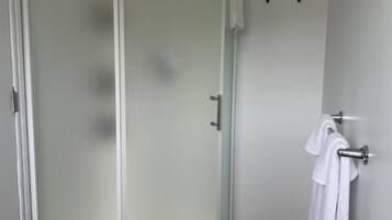 A modern bathroom with a glass-enclosed shower, a white sink, and a towel rack.