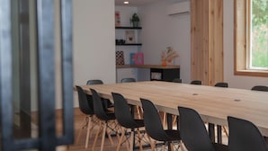 A conference room with a long wooden table, black chairs, and a wooden wall. - Hotel Le Riviera (Rawdon)
