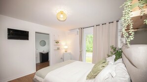 A bedroom with a large bed, a bedside table with a lamp, a mirror, and a window with curtains. - Hotel Le Riviera (Rawdon)