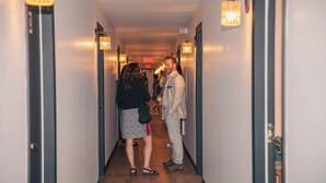 A hallway with a wooden floor and walls, featuring a series of doors with light fixtures above them. - Hotel Le Riviera (Rawdon)