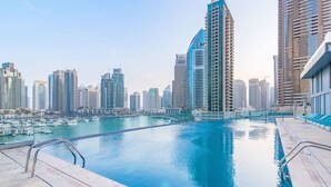 A swimming pool with a cityscape view, surrounded by high-rise buildings. - Iconic Marina Stay Cayan Tower 2BR (Dubai)