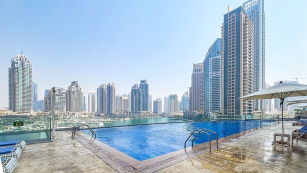 Une piscine sur le toit offrant une vue panoramique sur la ville, entourée d’immeubles de grande hauteur.