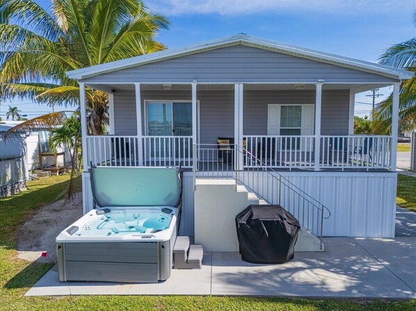 Een gelijkvloers huis met een overdekte veranda, een hottub en een overdekte barbecue.