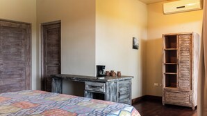 Une chambre à coucher comprenant un lit, un bureau en bois, une armoire et un climatiseur fixé au mur.