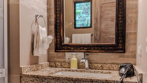 Une salle de bain avec un comptoir en granit, un lavabo, un miroir et un sèche-cheveux.