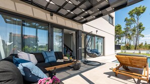 Un espacio exterior moderno con sofá, sillón colgante y banco de madera.