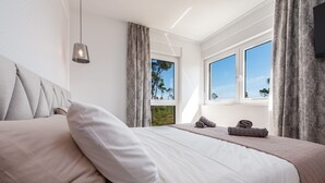 Un dormitorio moderno con una cama grande, vistas al exterior y una lámpara colgante.