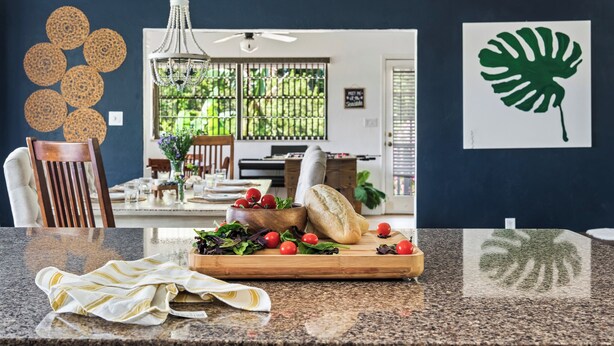 A kitchen counter with a cutting board, vegetables, and a loaf of bread.