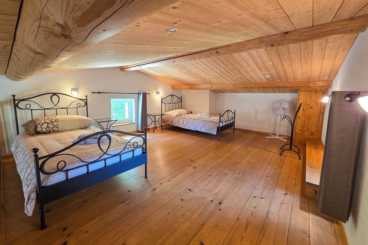 A bedroom with two beds, wooden floors, and a sloped ceiling.