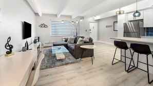 A modern kitchen with a built-in refrigerator and a dining area with bar stools. - Beautiful remodeled 1-bedroom condo in Littleton/ Englewood with Pool (Englewood)