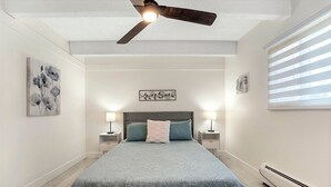 A bedroom with a bed, a ceiling fan, wall art, and a window with blinds. - Beautiful remodeled 1-bedroom condo in Littleton/ Englewood with Pool (Englewood)