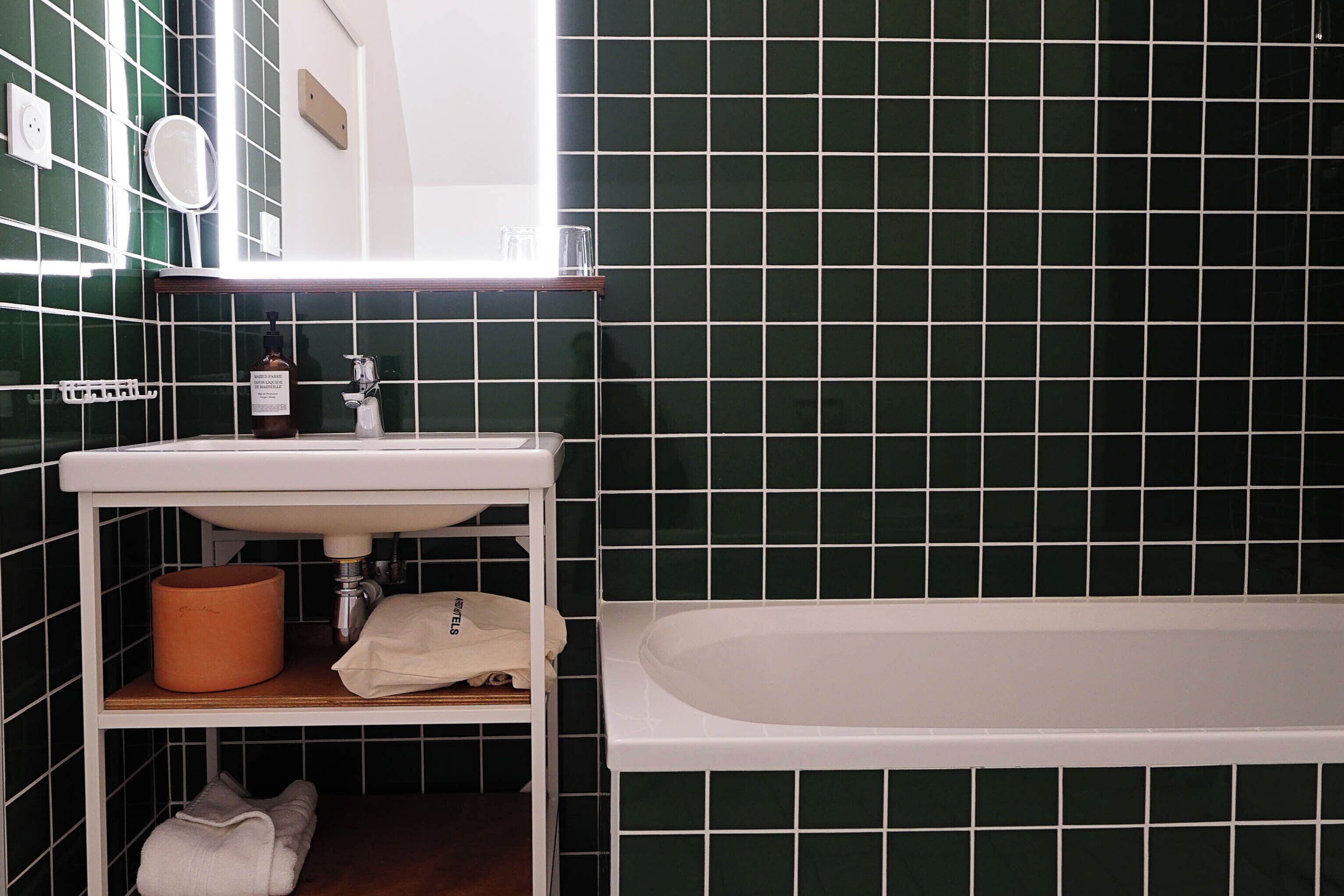 Un baño con lavamanos blanco, espejo y bañera.