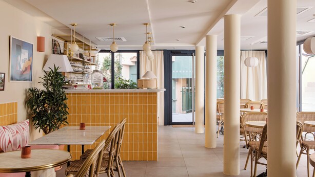 Un restaurante con barra de baldosas, mobiliario de mimbre e iluminación colgante.