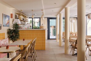 A restaurant with a tiled bar area, wicker furniture, and pendant lighting. - Alfred Hotels Toulouse Centre Wilson - Hôtel Rénové  (Toulouse)