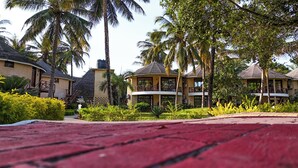 A resort with multiple buildings, including a two-story structure with balconies and a smaller building with a curved roof. - Kae Beach Resort (Michamvi)