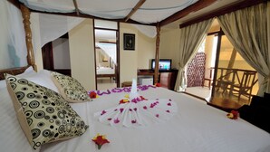 A hotel room with a bed, a television, a balcony, and a wooden chair. - Kae Beach Resort (Michamvi)