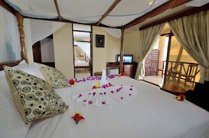Habitación de hotel con cama, televisión, balcón y una silla de madera.