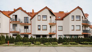 Un filare di moderni palazzi con balconi, un piano terra lastricato e un’area giardino curata.
