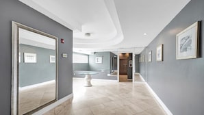 A modern hotel corridor with grey walls, a marble floor, and framed artwork. - Ocean Dr 1BR Miami Beach Getaway (Miami Beach)