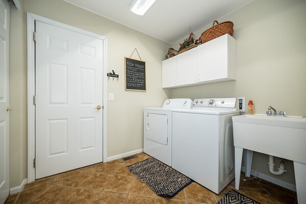 A laundry room with a washer and dryer, a white sink, and a wall-mounted basket.