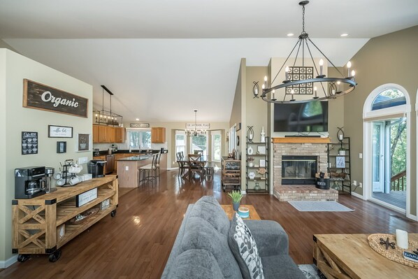 A spacious living room with a fireplace, a coffee station, and a dining area.