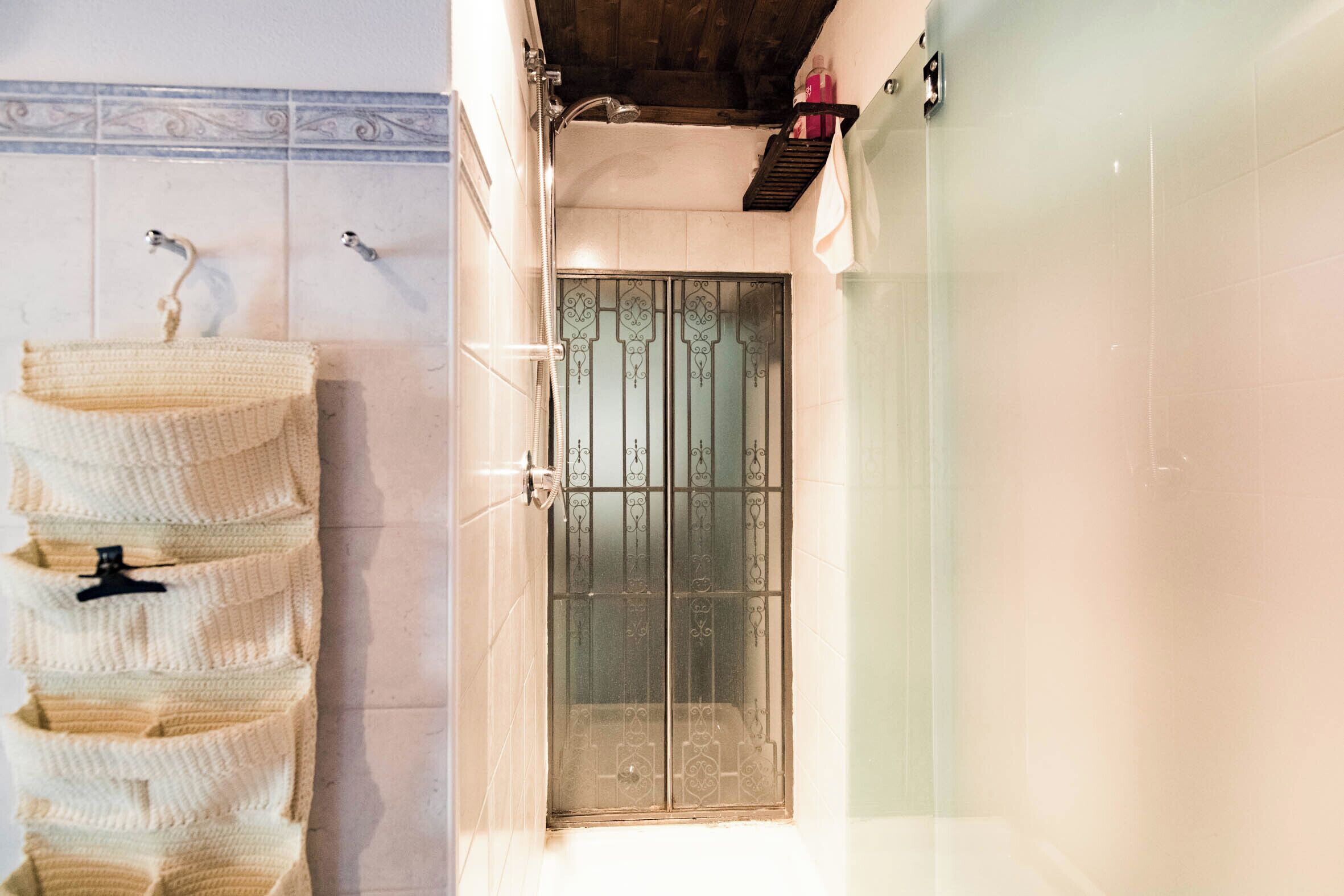 Ein Badezimmer mit gefliesten Wänden, einem Waschbecken mit Handtuchhalter und einer Duschkabine.