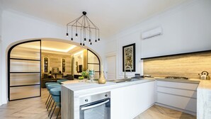 A modern kitchen with a built-in oven, a dining area with blue chairs, and a kitchen island with bar stools.