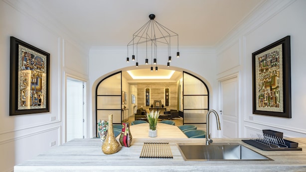 A modern kitchen with a central island, a built-in sink, and a dining area visible through an archway.