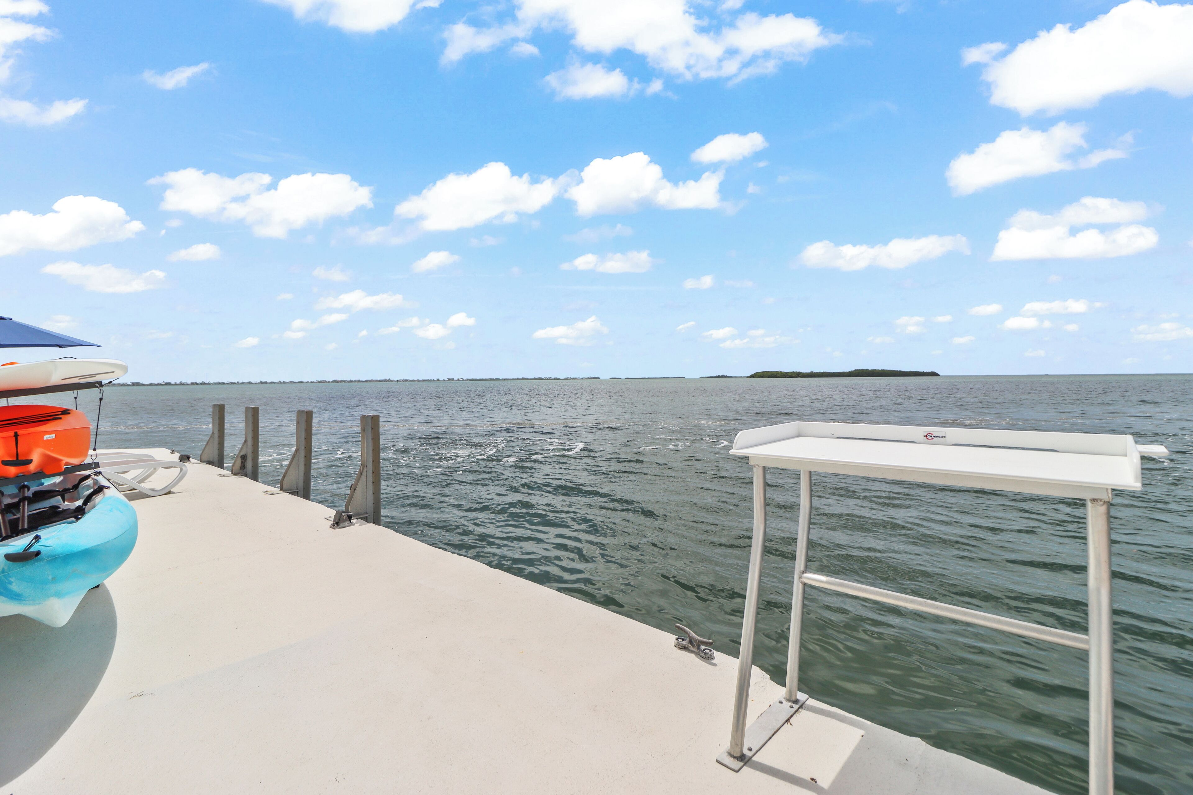 A boat docked at a pier with a clear view of the water and a distant island.