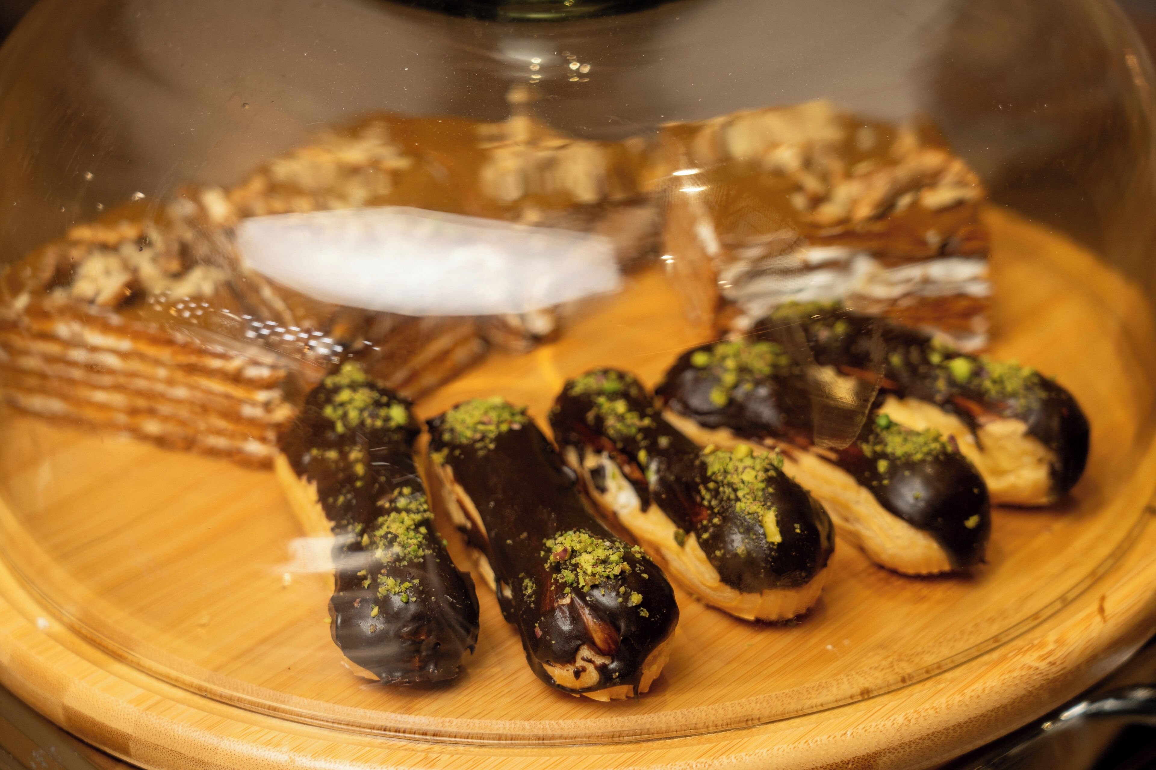 Et dessertfad med forskellige kager, heriblandt chokoladeovertrukne sager og en lagkage, på en træplade.