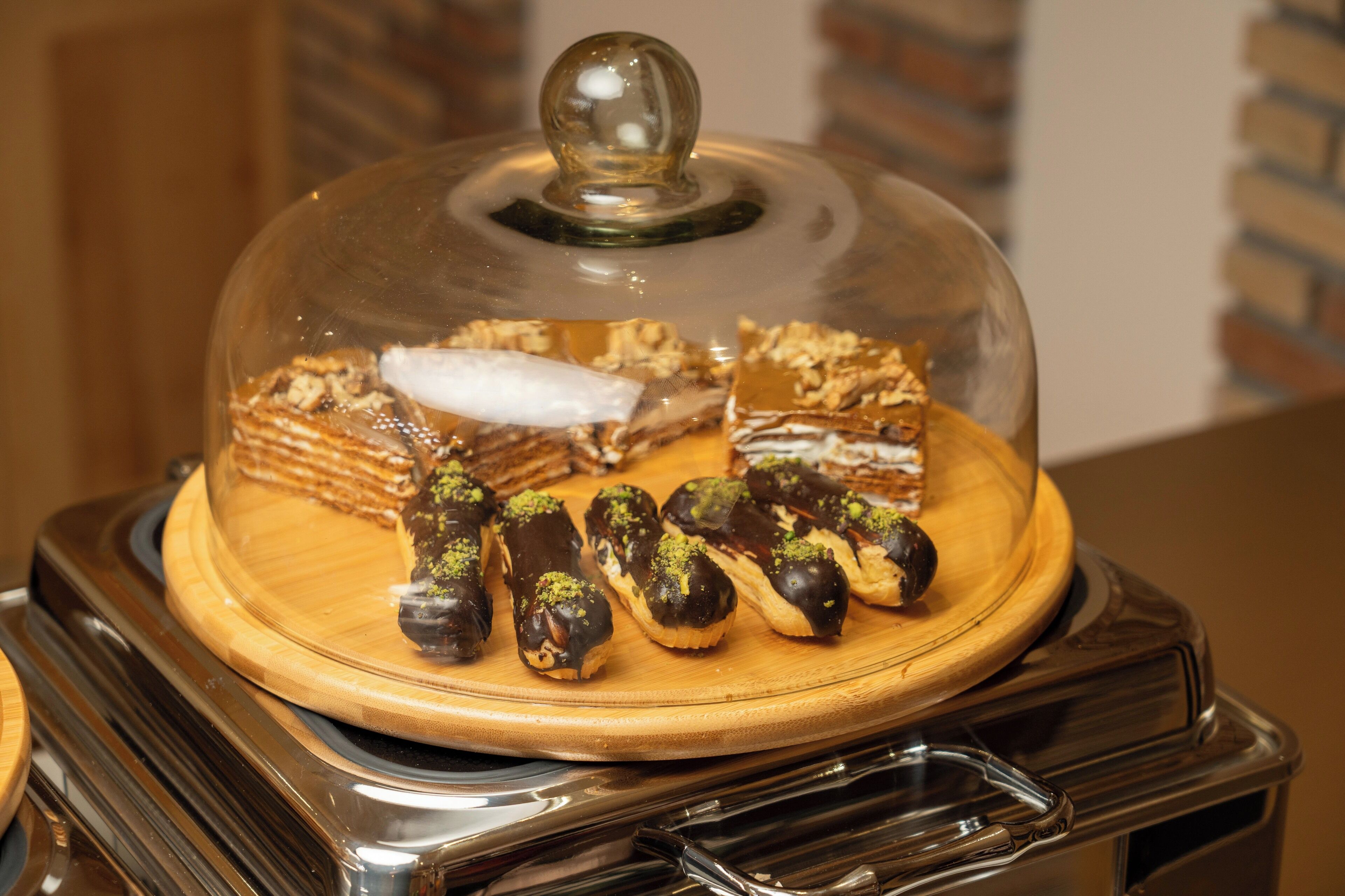 A dessert display with various pastries under a glass dome.