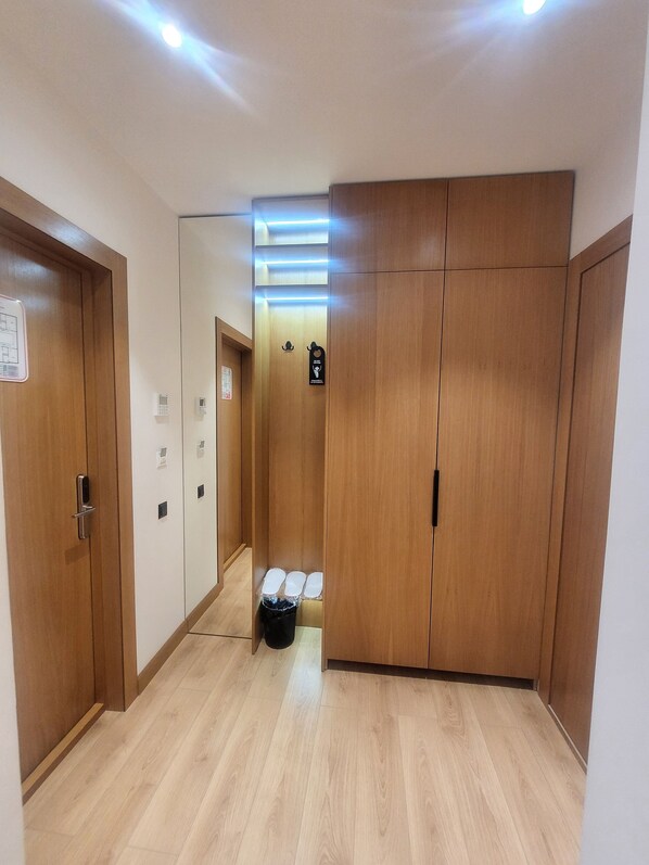 A hallway with wooden doors, a trash bin, and a sign indicating a smoking area. - Sarhad Hotel (Bukhara)