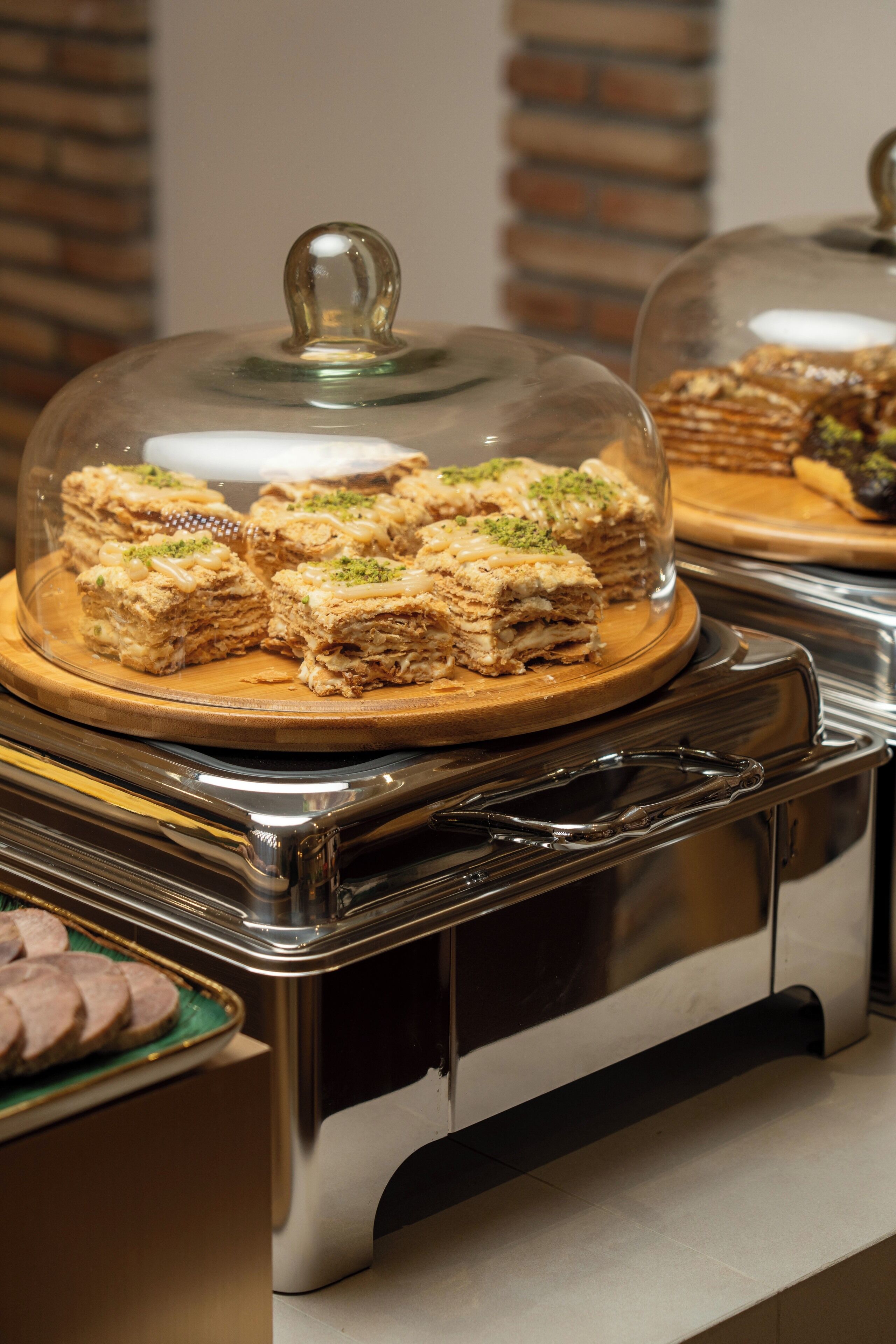 Un buffet proposant une variété de desserts, notamment des gâteaux à plusieurs couches et des pâtisseries, présentés sous des cloches de verre.