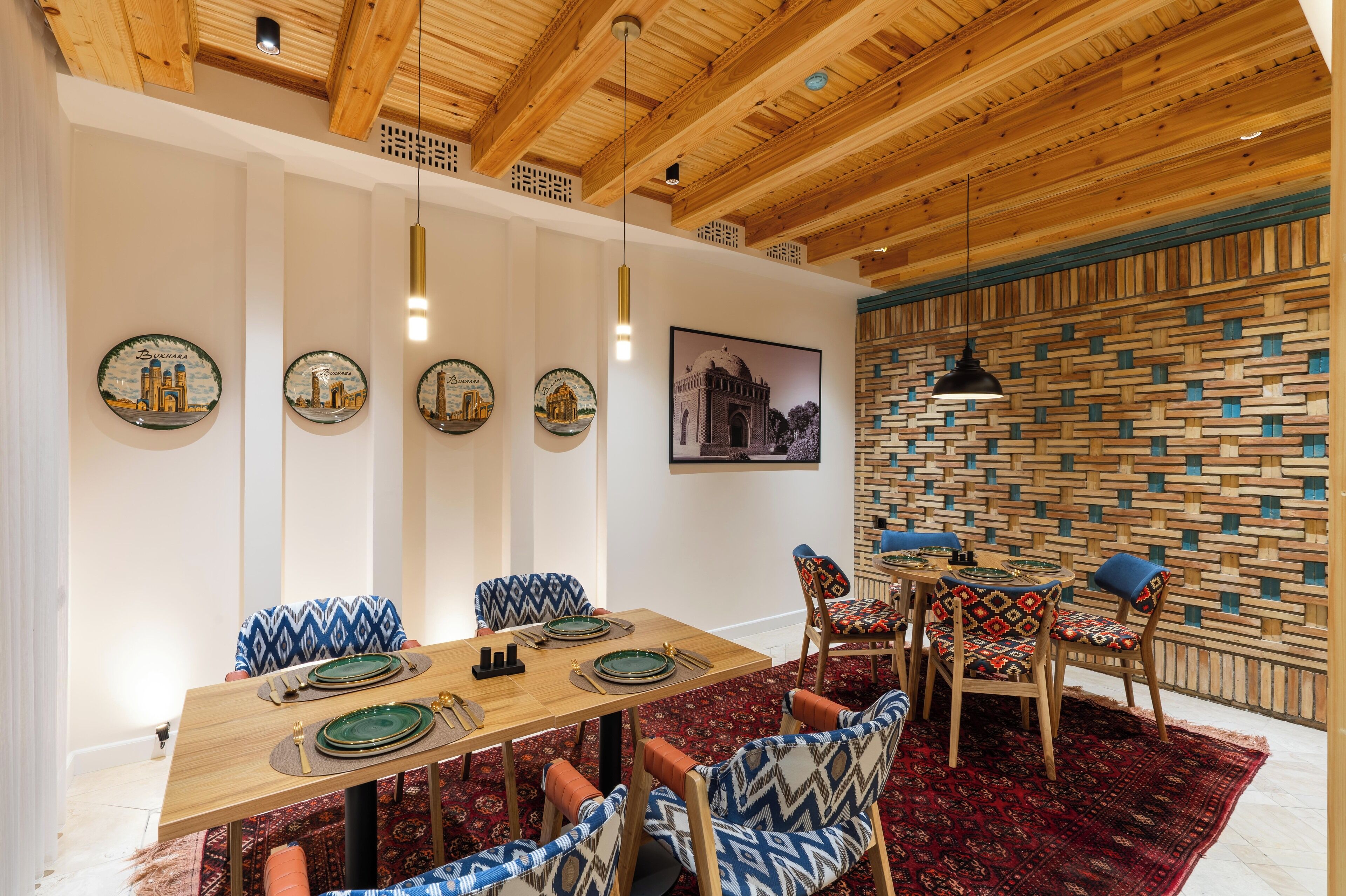 A dining area with a wooden table, patterned chairs, and a red carpet.