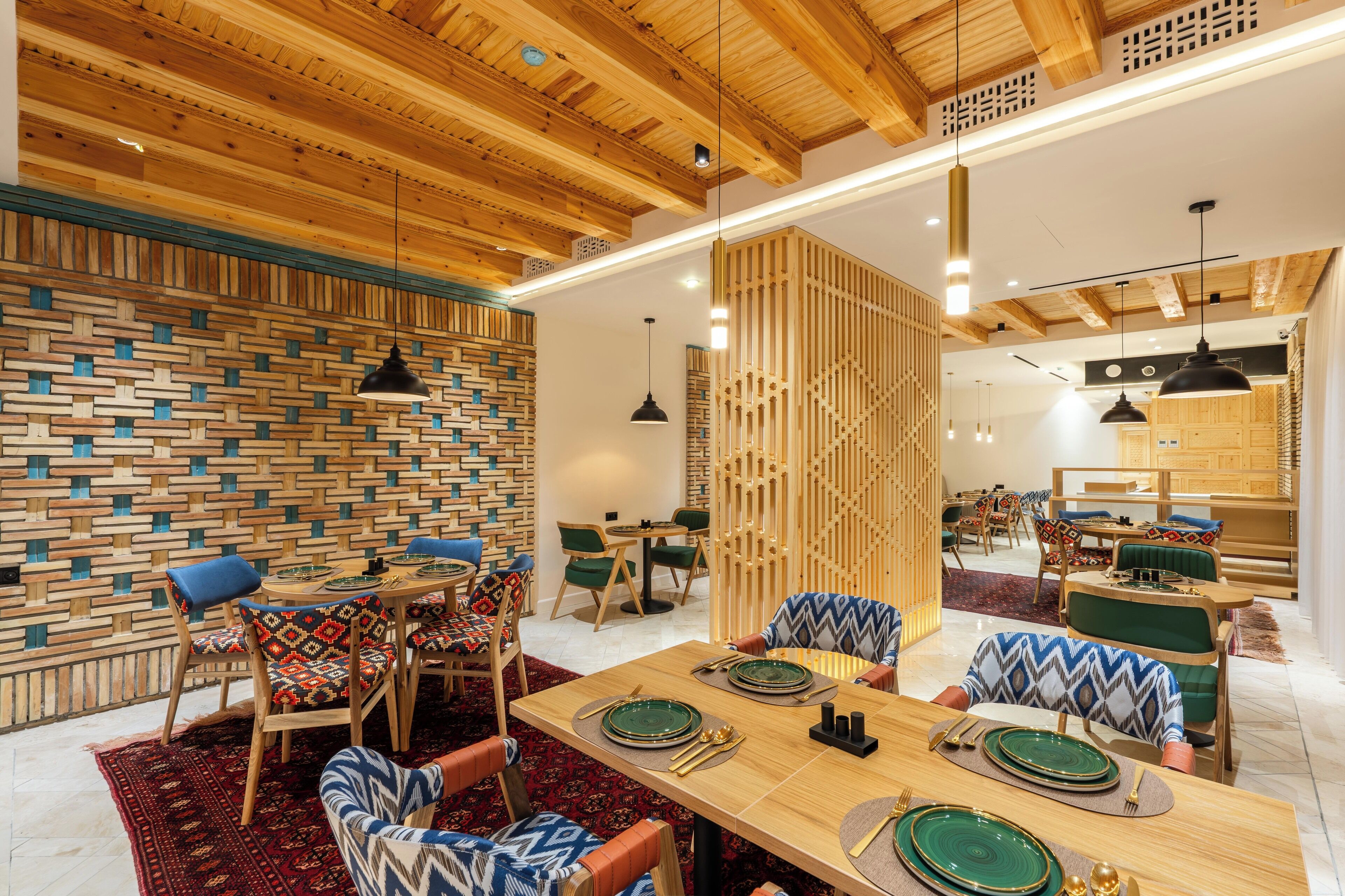 A modern dining area with wooden ceiling beams, a patterned wall, and a mix of wooden and upholstered chairs.