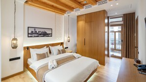 A modern hotel room with a wooden ceiling, a large bed with white bedding, a wooden desk, and a view of the outside balcony. - Sarhad Hotel (Bukhara)