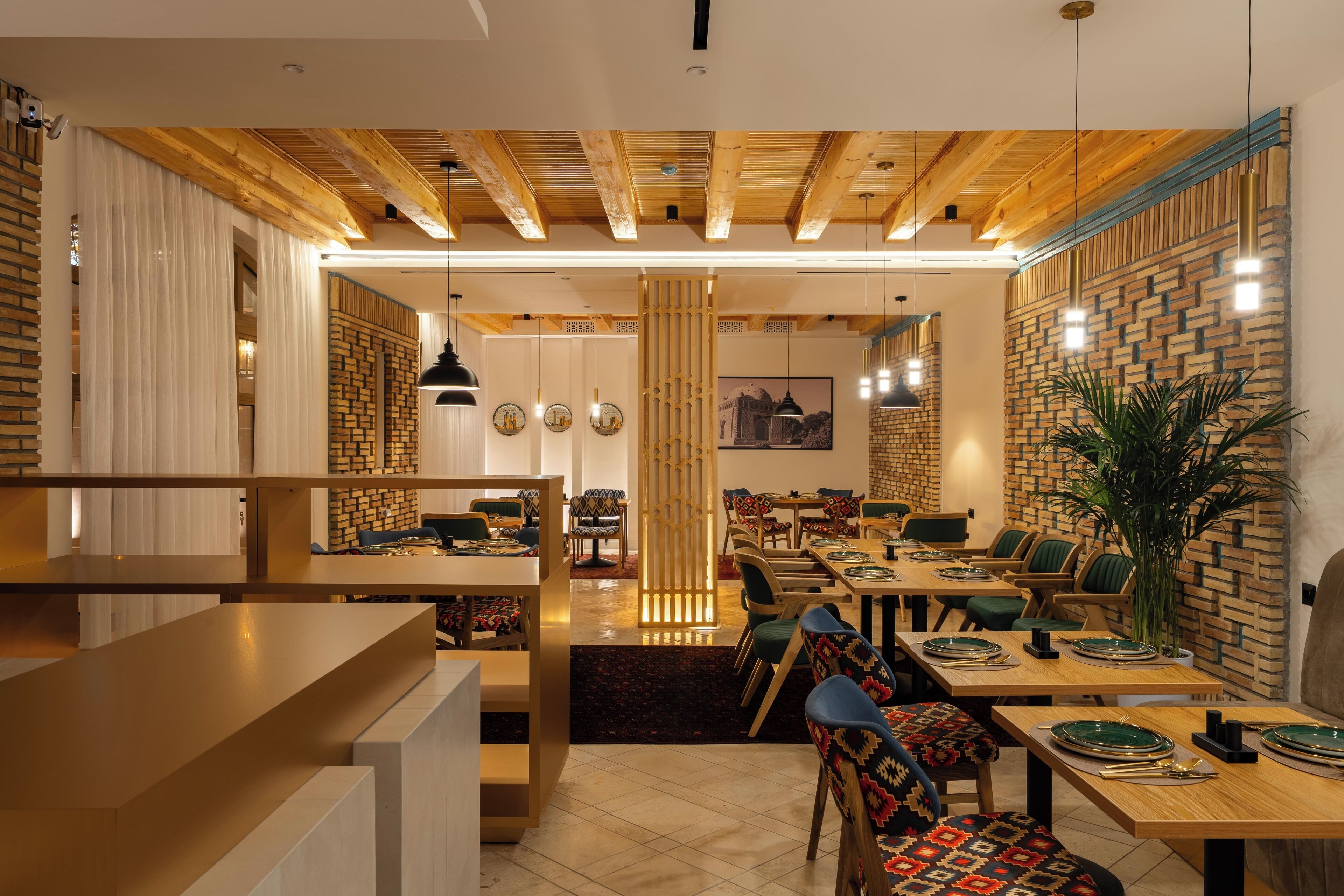Een modern restaurant met houten balken, bakstenen muren en verschillende zithoekopstellingen, waaronder tafels en stoelen.