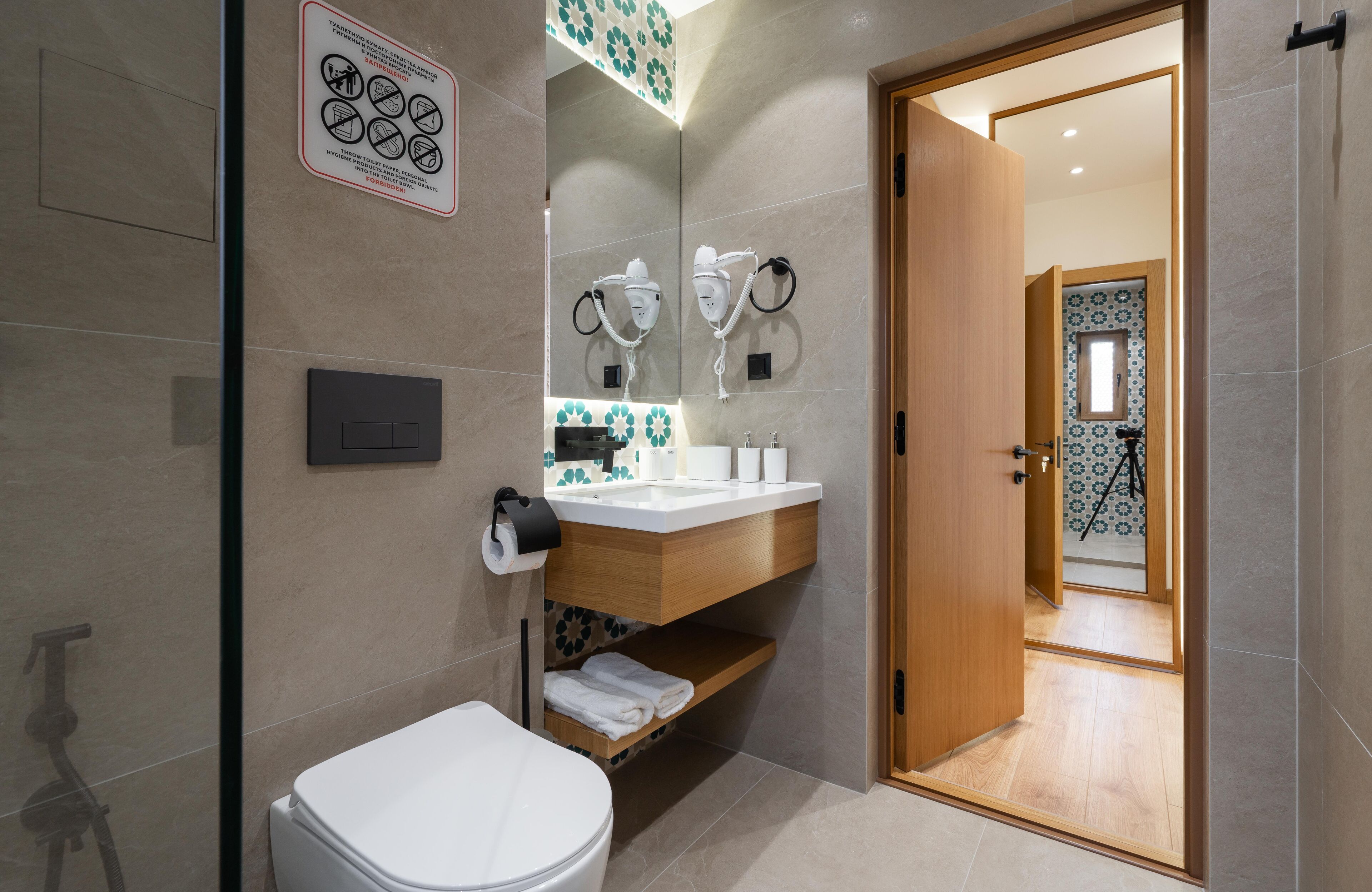 A modern bathroom with a toilet, sink, and hairdryer mounted on the wall.